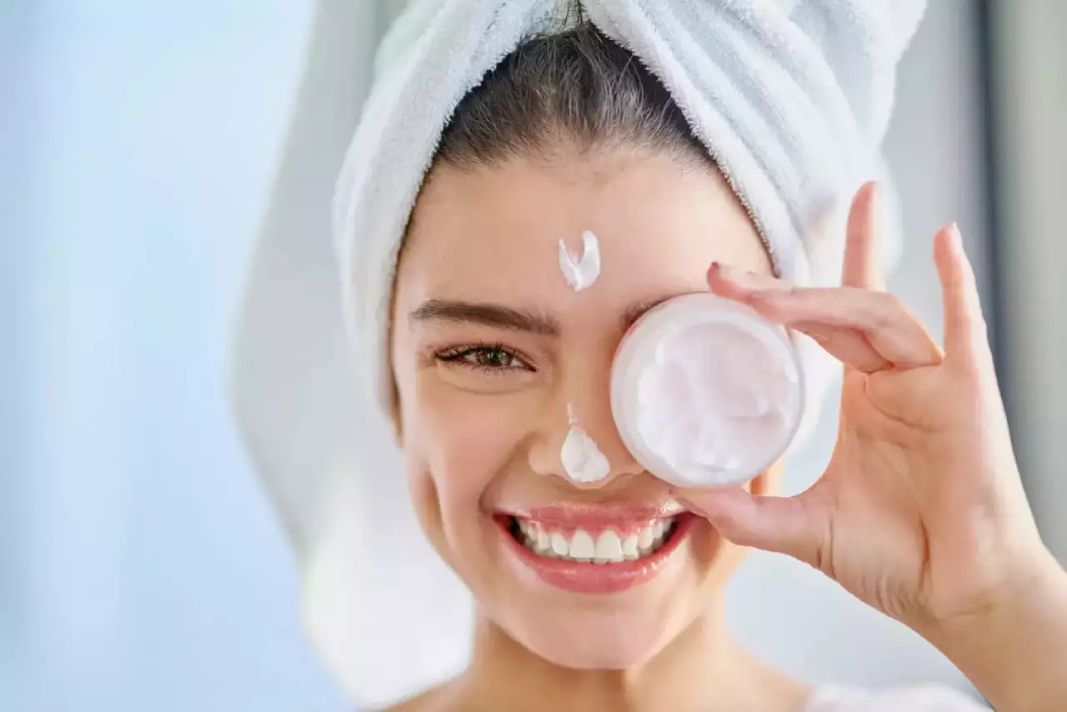 A women holding moisturizer in front of her face