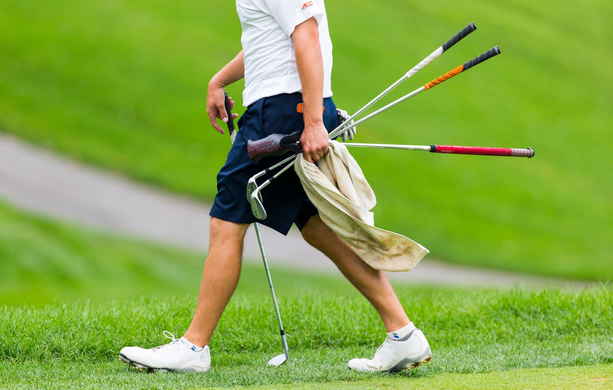 a golfer carrying golf clubs in his hands on the field