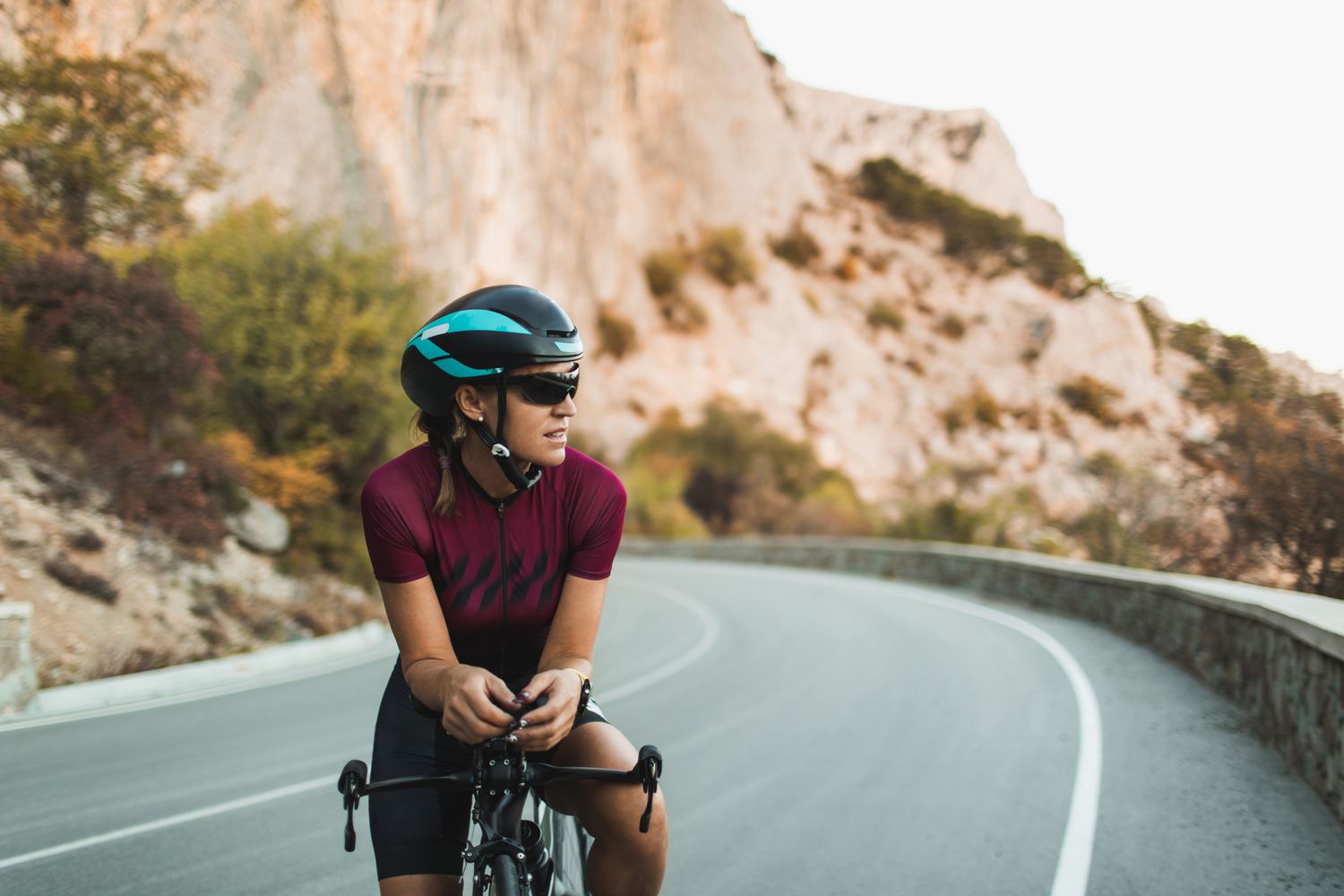 a cyclist posing on the cycle on a road wearing a helmet and sunglasses