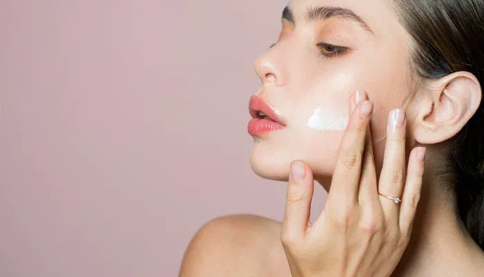 a woman applying moisturizer on her face