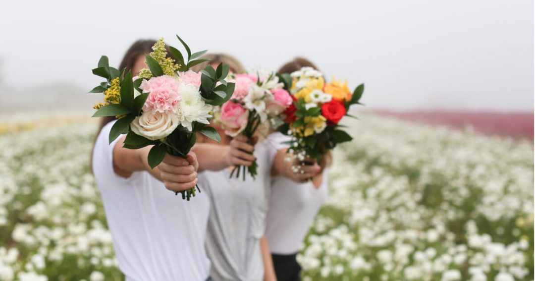an image of friends holding flower bouquets in front of their faces