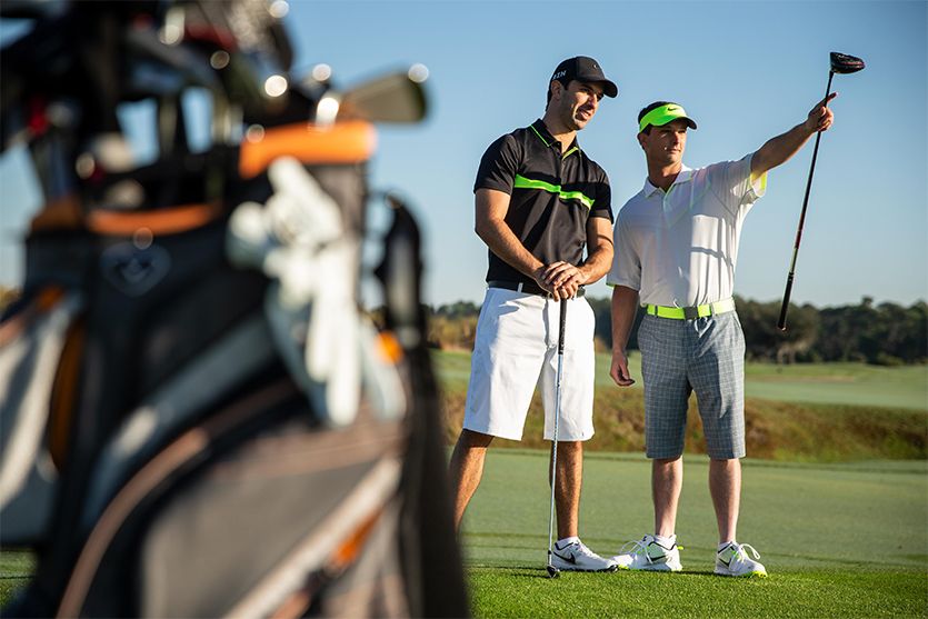 two golfers holding golf club in the golf field